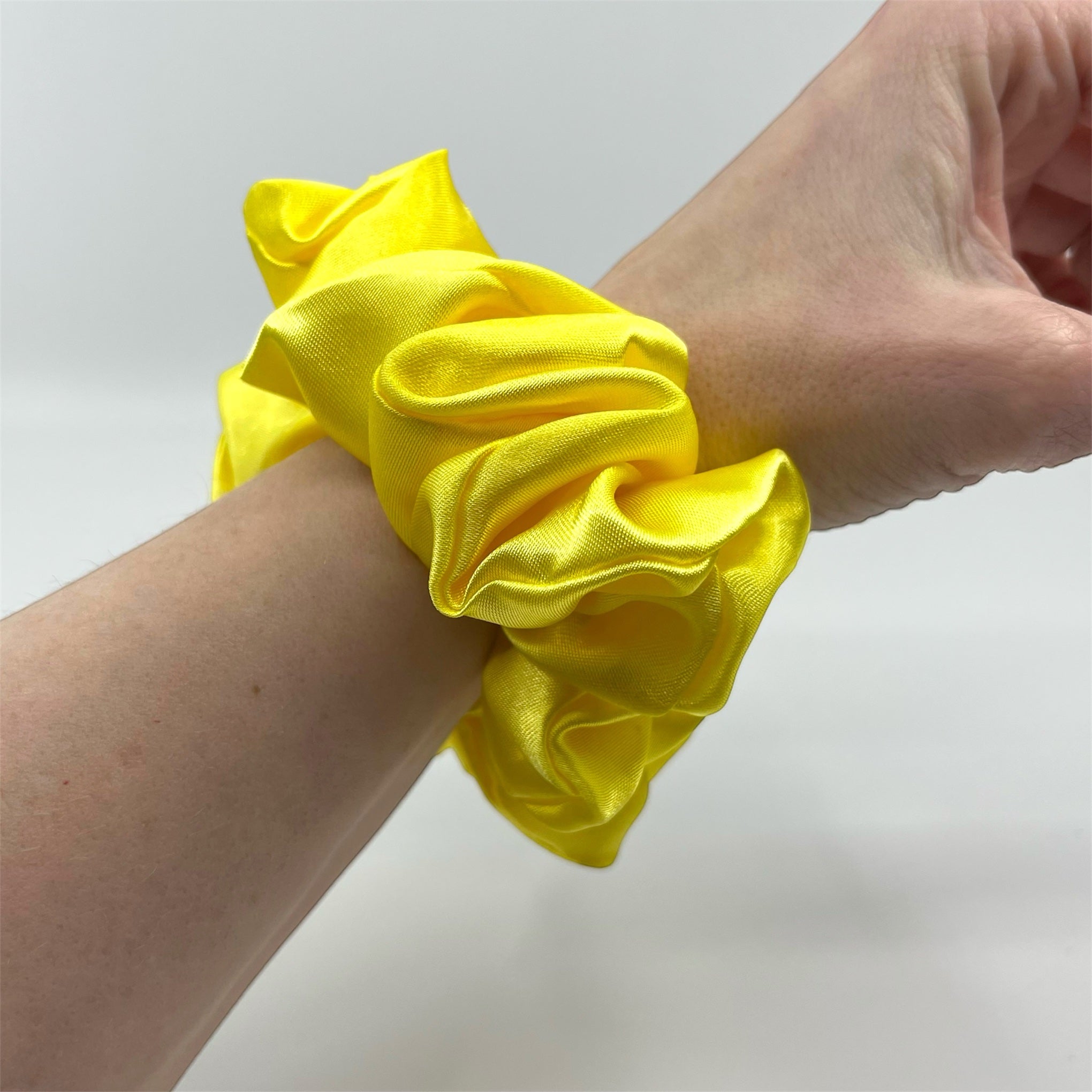 ljusgul classic satin scrunchie på handleden
