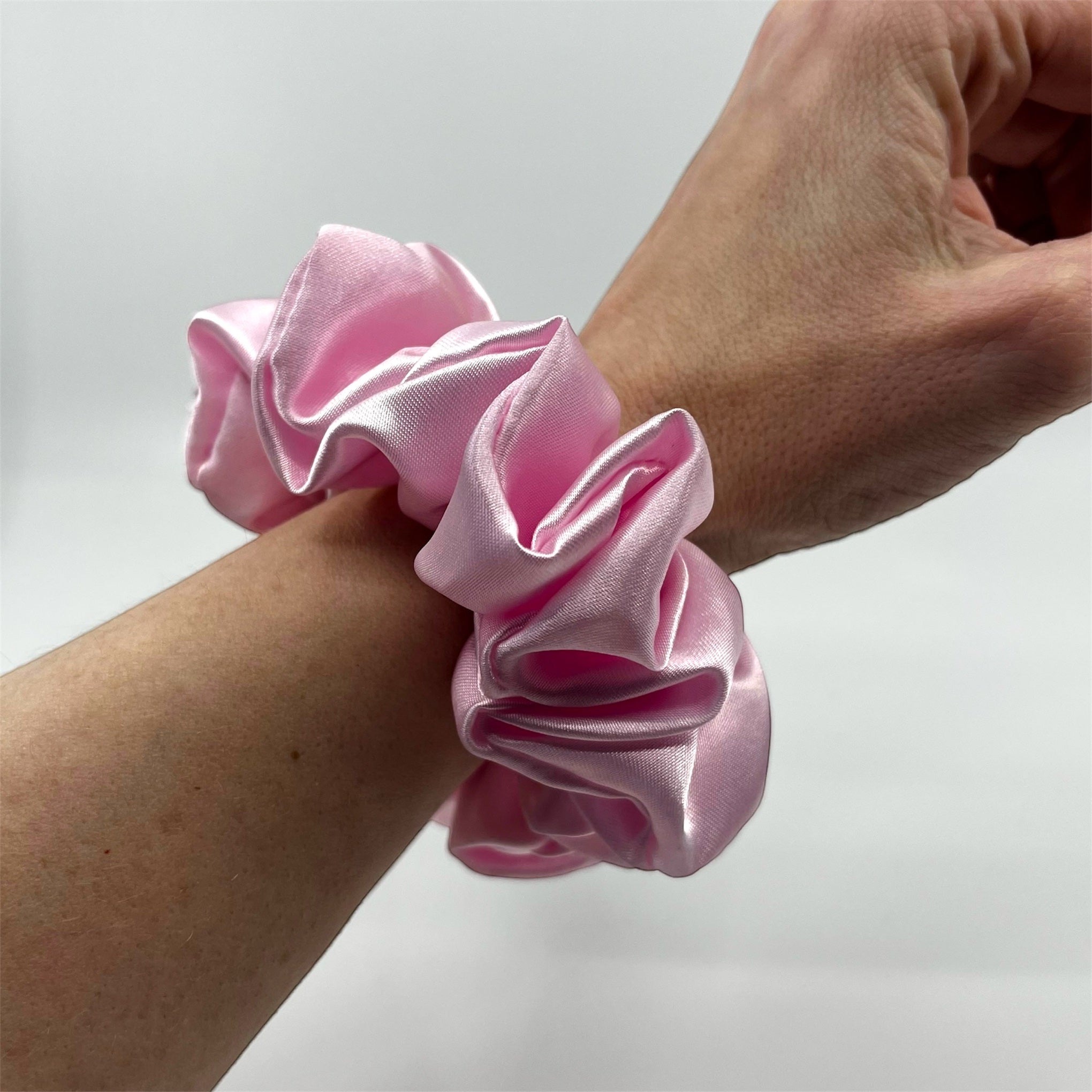 ljusrosa classic satin scrunchie på handleden