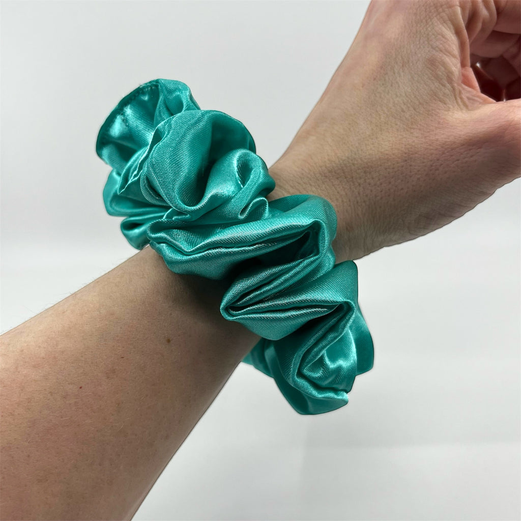 mörk mintgrön classic satin scrunchie på handleden