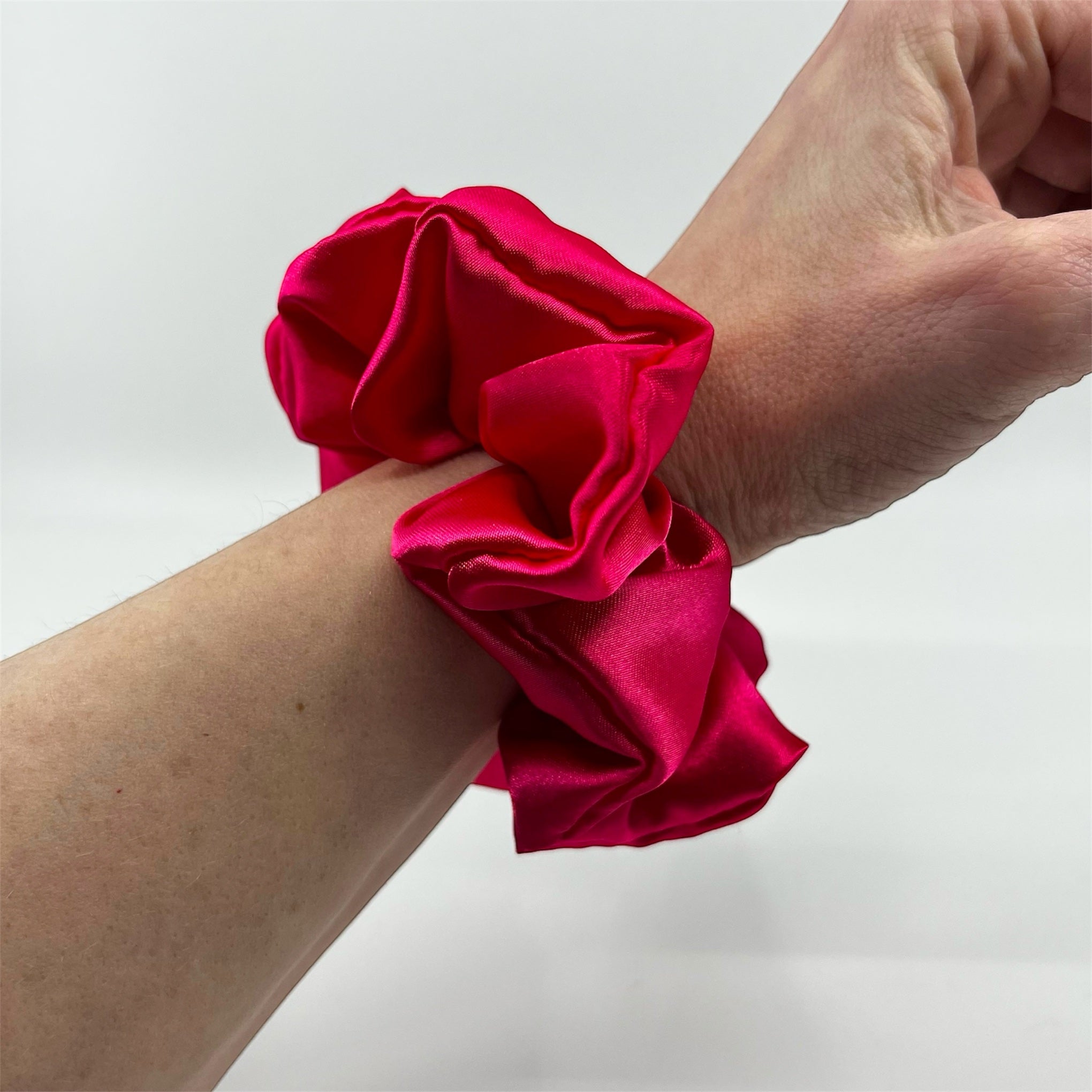 mörkrosa classic satin scrunchie på handleden