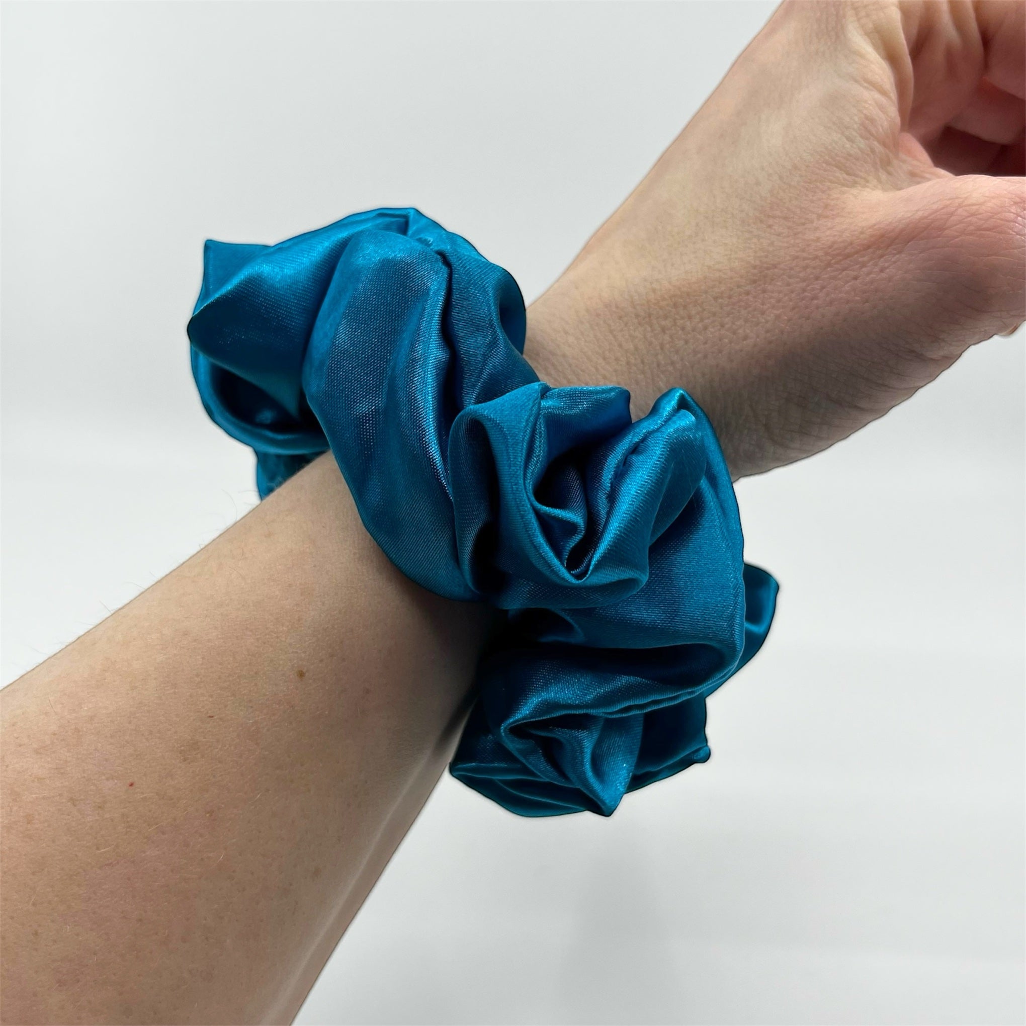 mörk turkos classic satin scrunchie på handleden