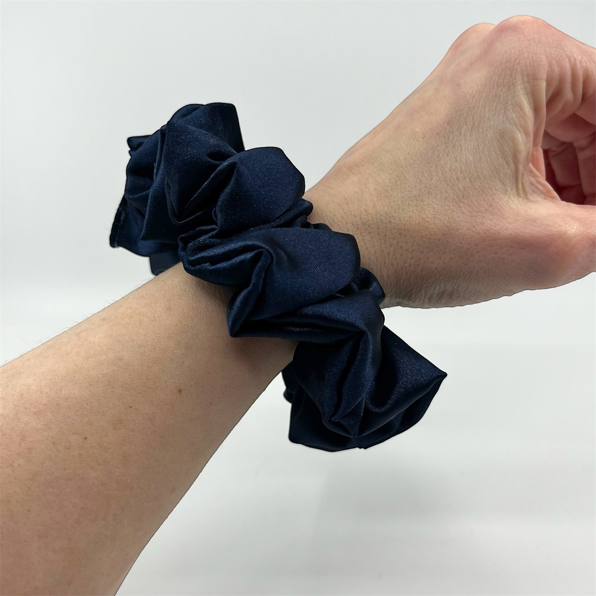 mörkblå classic satin scrunchie på handleden