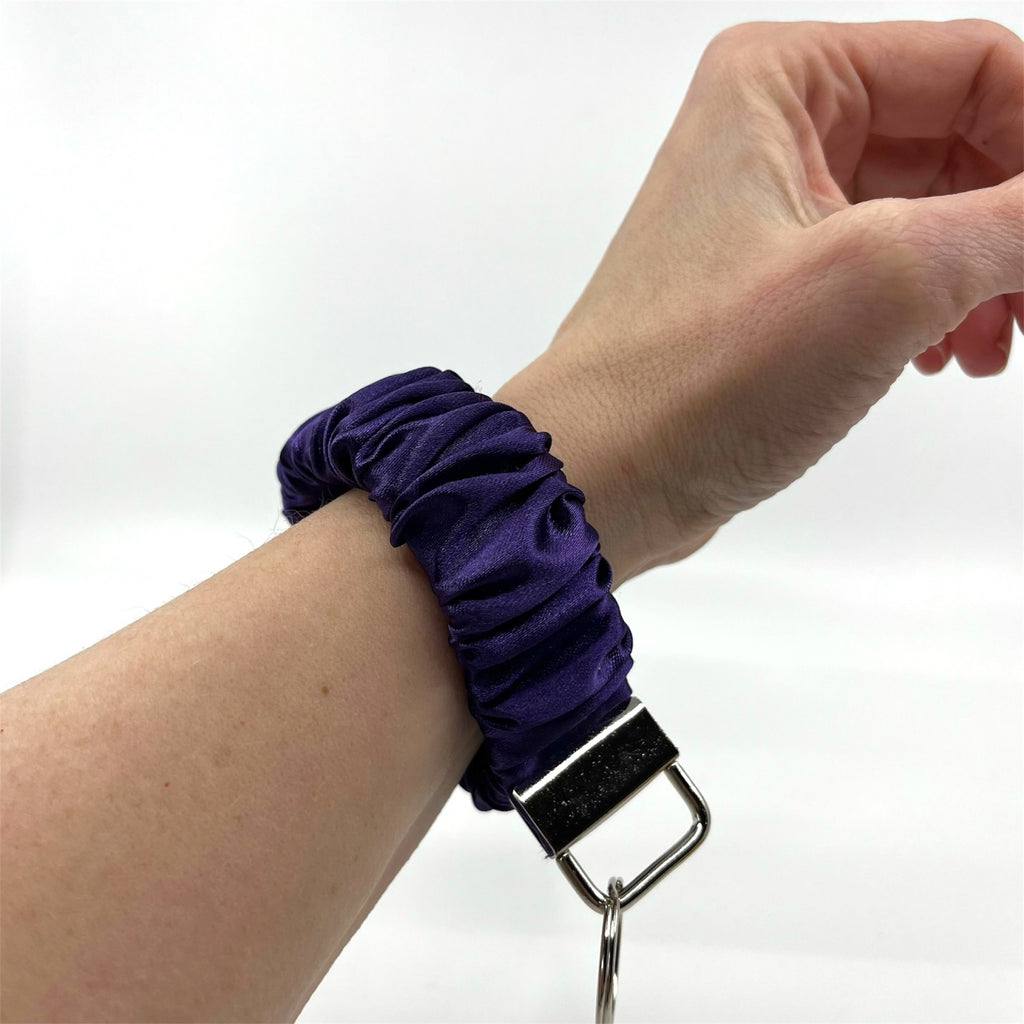 mörklila scrunchie nyckelring på handleden