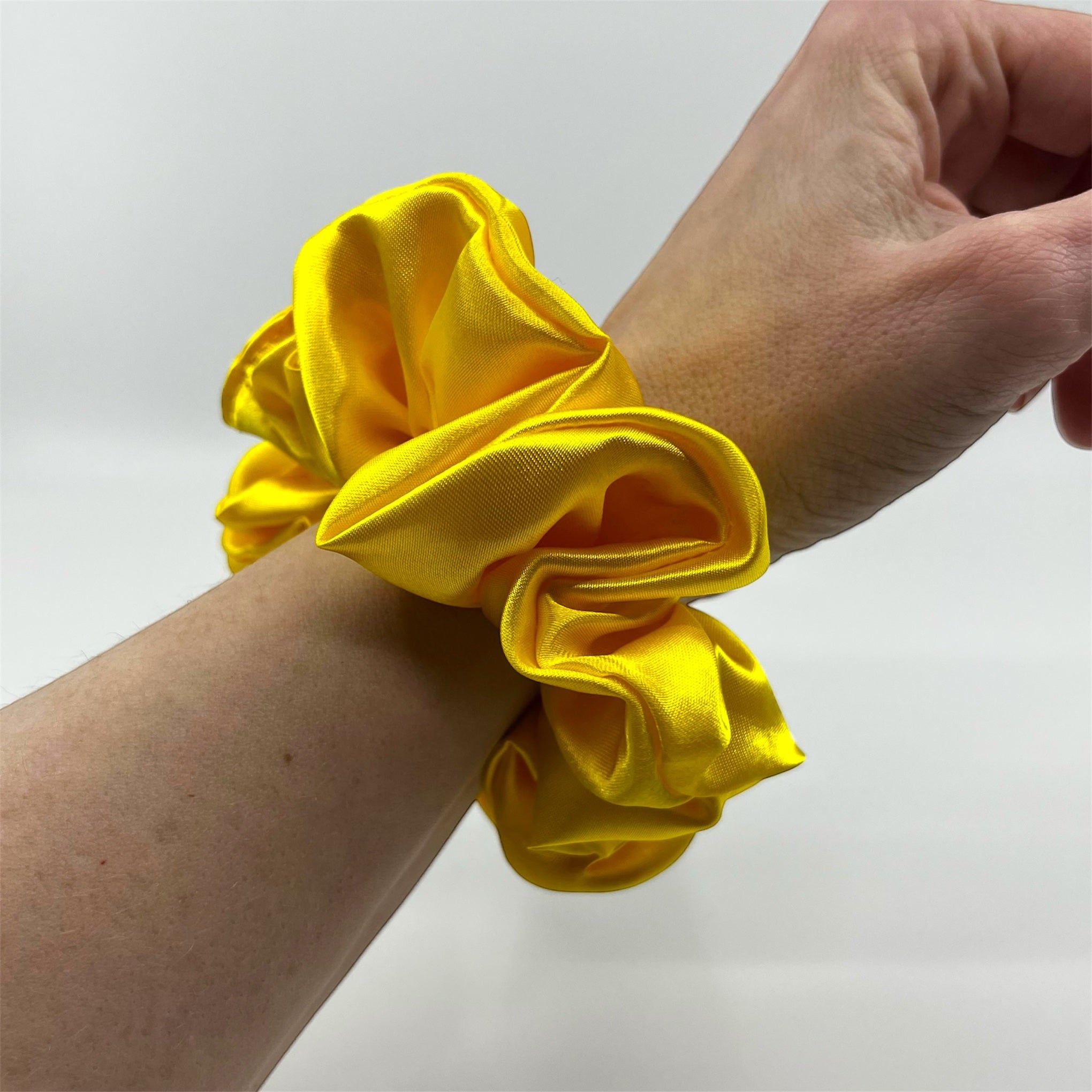 gul glassic satin scrunchie på handleden