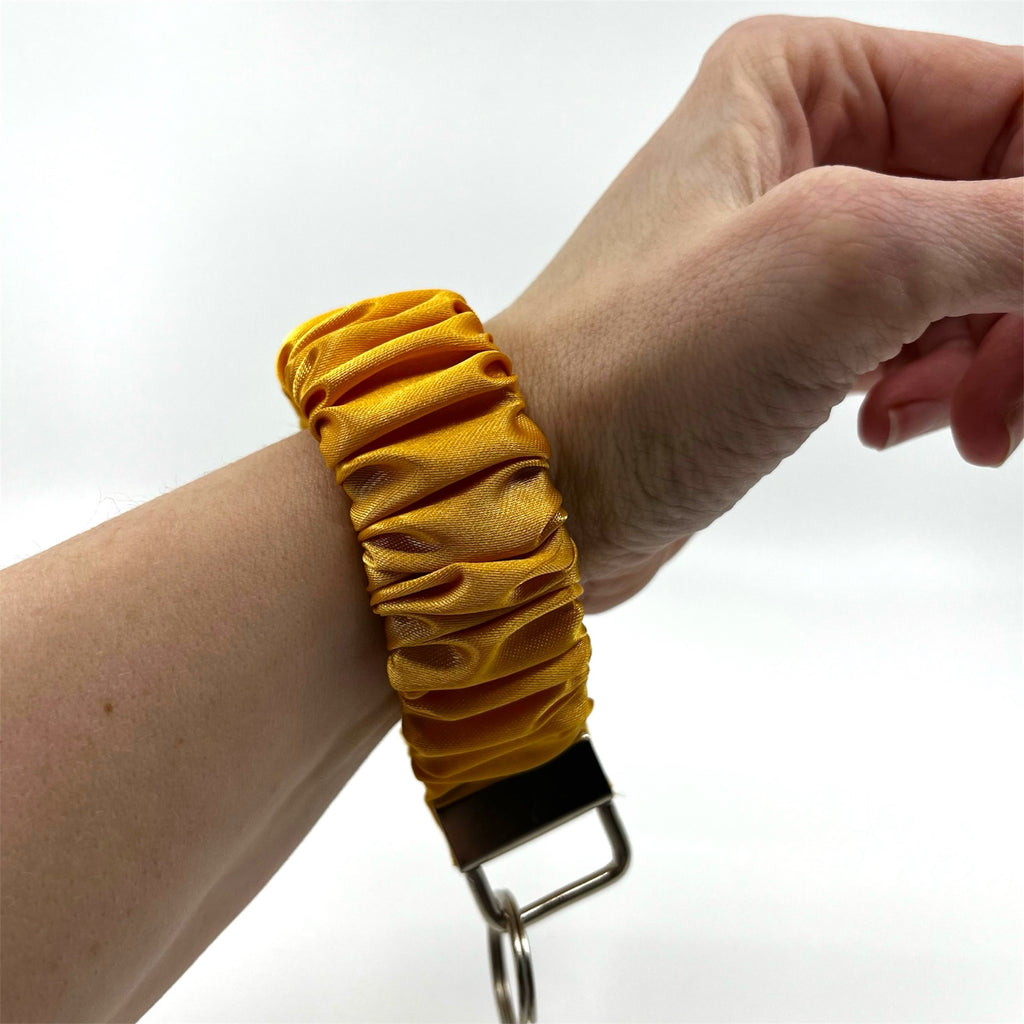 solgul scrunchie nyckelring på handleden